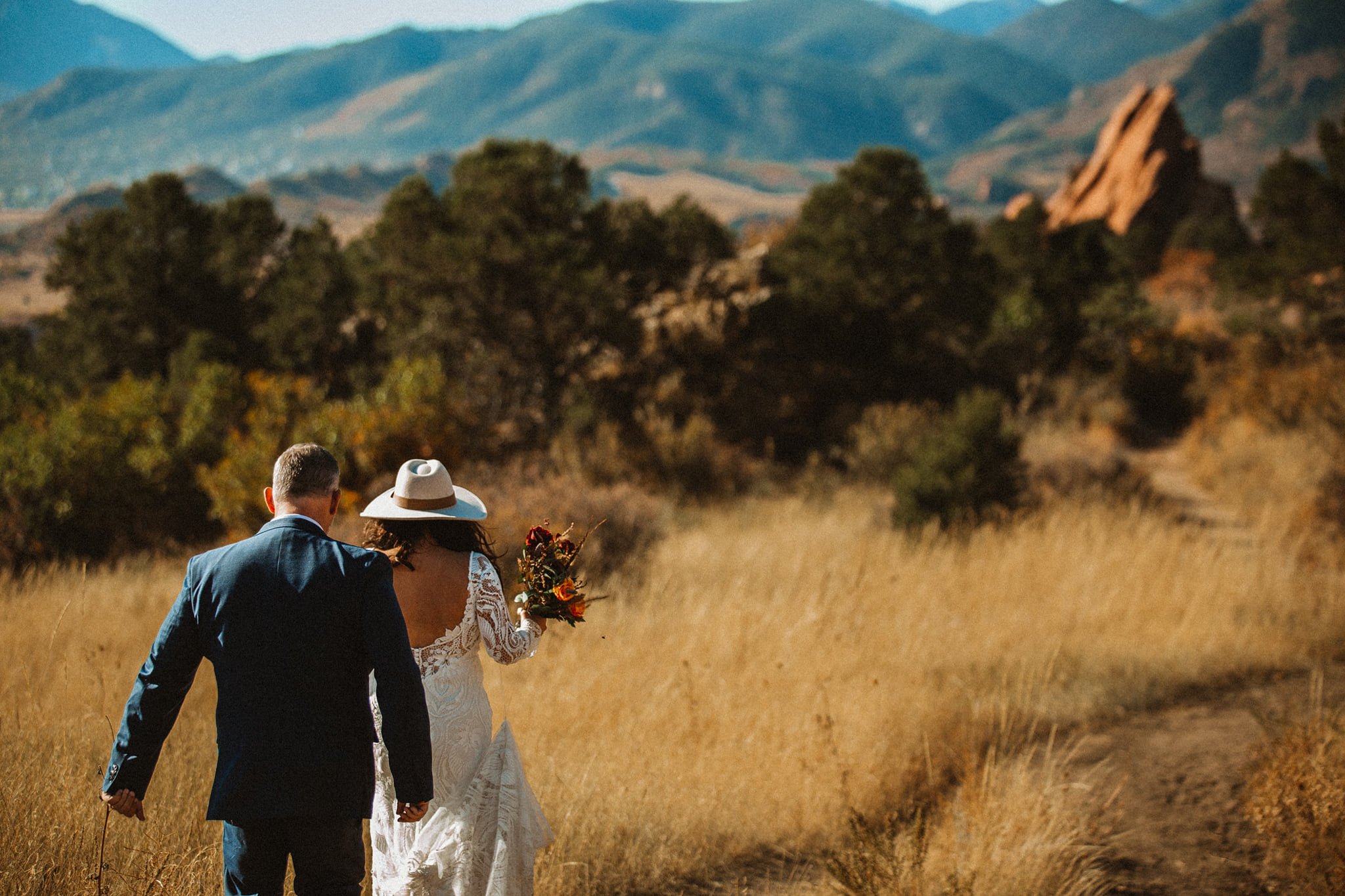 garden of the gods sunrise  elopement bride and groom walking with flowers