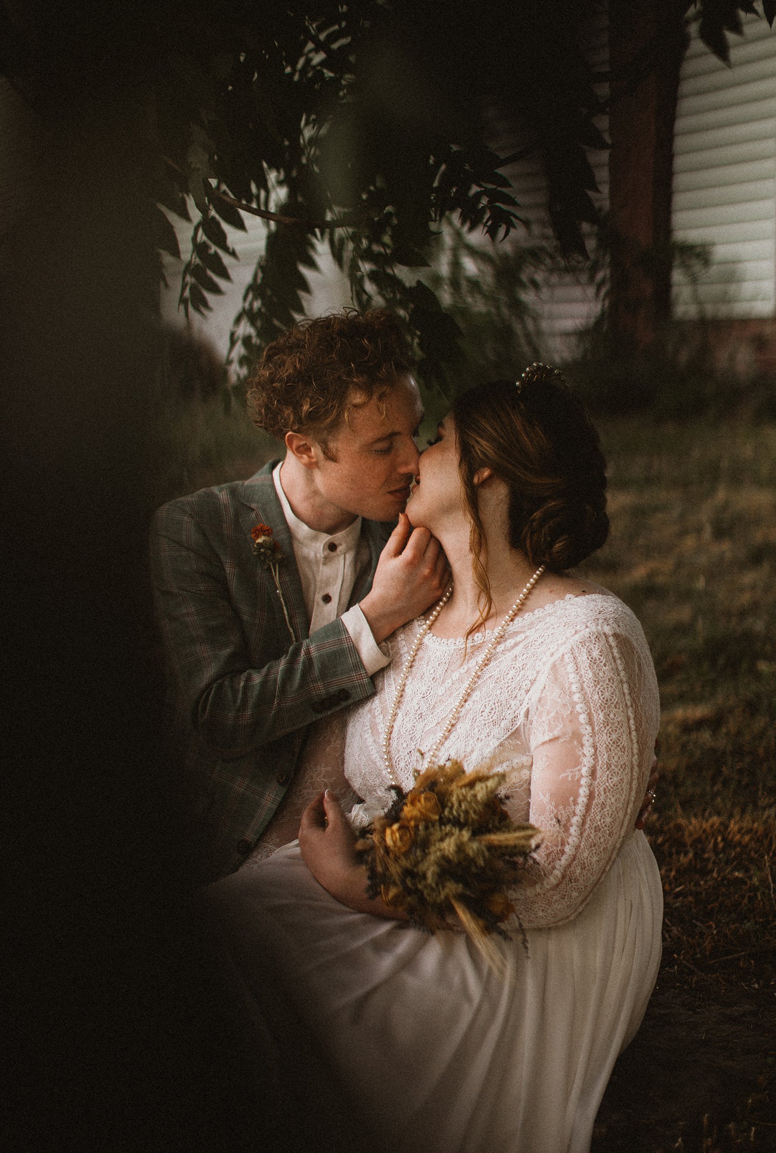 bride and groom kiss under tree