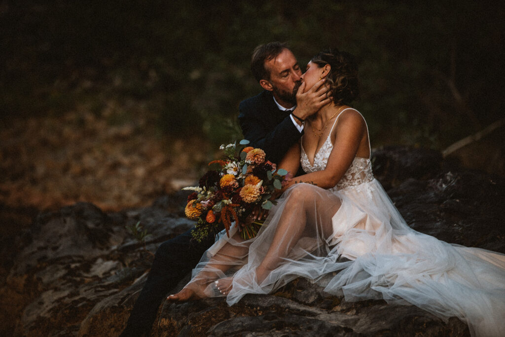 Newly married bride and groom kiss by a river in Durango 